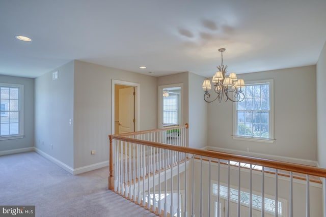 corridor featuring a chandelier, carpet, a healthy amount of sunlight, and baseboards