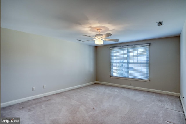 carpeted spare room featuring ceiling fan, visible vents, and baseboards