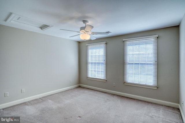 unfurnished room featuring attic access, carpet floors, baseboards, and a ceiling fan