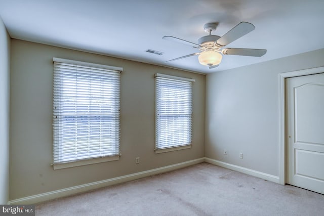 carpeted empty room featuring ceiling fan, visible vents, and baseboards