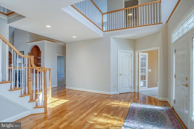 entrance foyer featuring baseboards, stairway, wood finished floors, a high ceiling, and recessed lighting