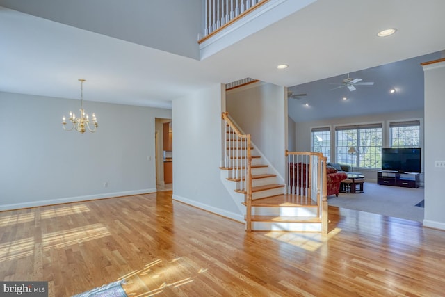 interior space featuring a towering ceiling, stairway, baseboards, and wood finished floors