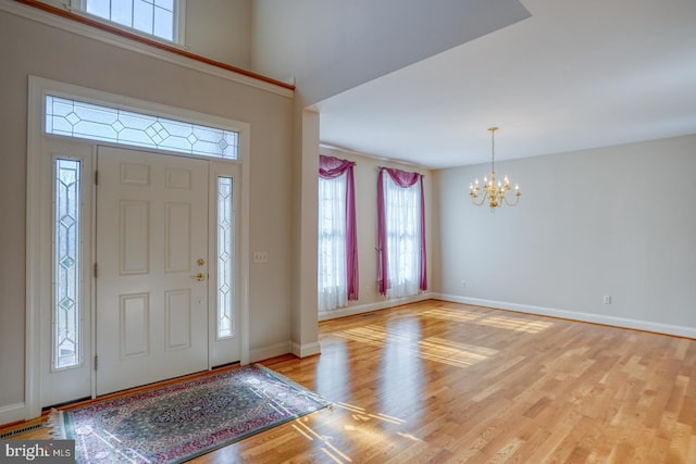 foyer featuring light wood-type flooring, baseboards, and an inviting chandelier