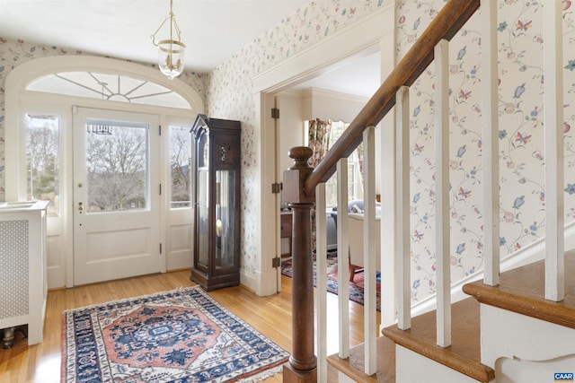 foyer with light wood-style floors, stairway, baseboards, and wallpapered walls