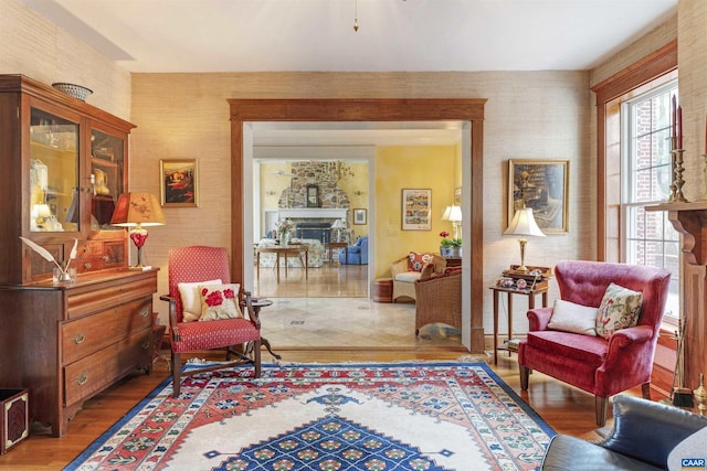 living area featuring wood finished floors, a fireplace, and wallpapered walls