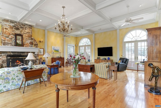 living area with a stone fireplace, beamed ceiling, coffered ceiling, and light wood-style flooring