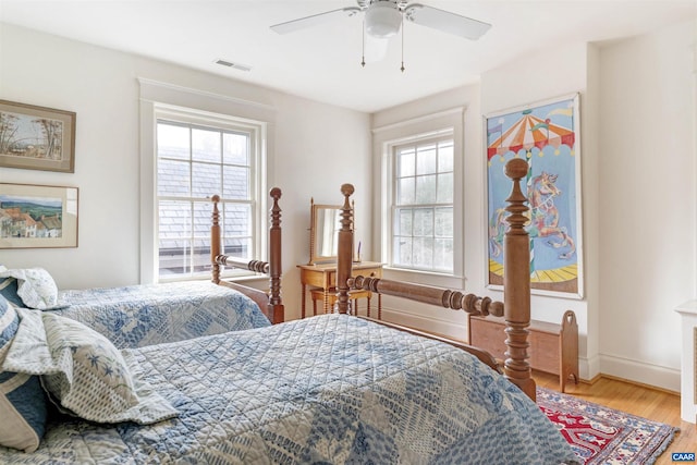 bedroom featuring multiple windows, wood finished floors, visible vents, and baseboards