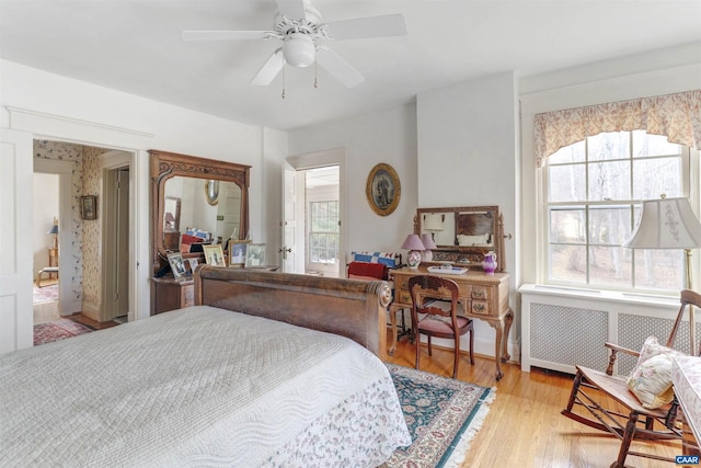 bedroom featuring radiator, light wood-style floors, and ceiling fan