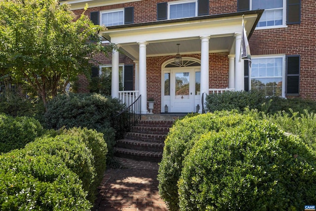 entrance to property featuring a porch and brick siding