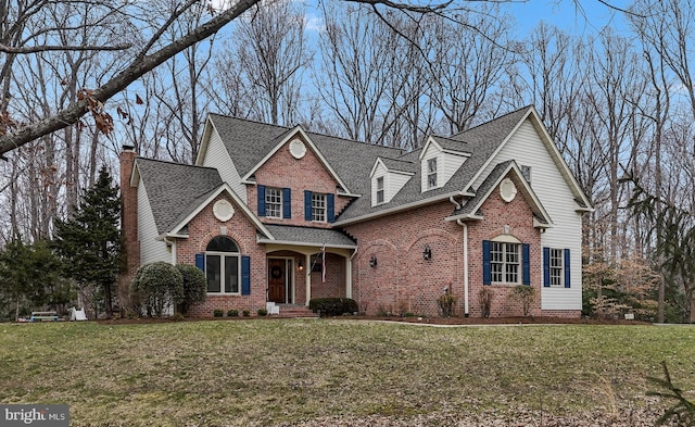 traditional-style home featuring brick siding, a front lawn, and roof with shingles