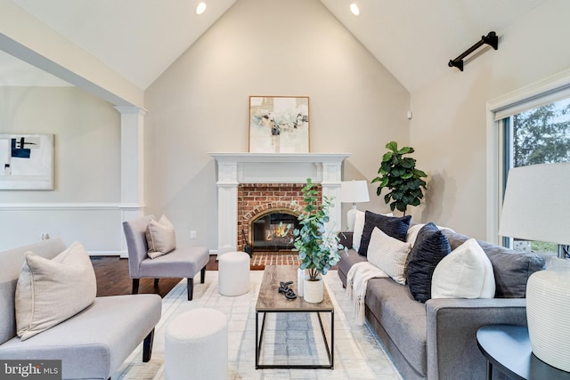 living area with baseboards, wood finished floors, a brick fireplace, high vaulted ceiling, and recessed lighting