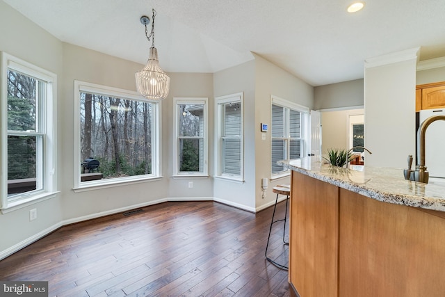 kitchen featuring visible vents, baseboards, light stone countertops, dark wood finished floors, and pendant lighting