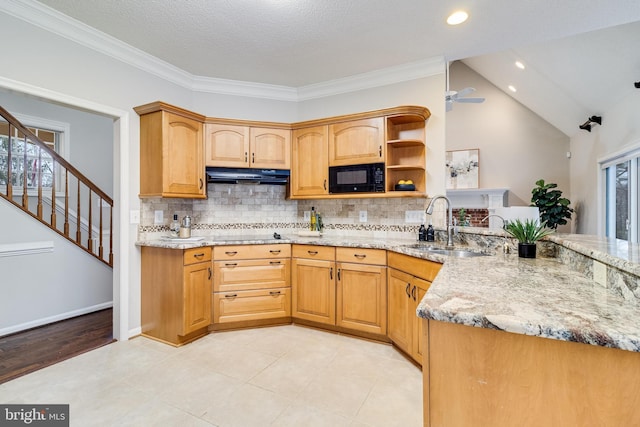 kitchen featuring decorative backsplash, light stone counters, under cabinet range hood, black appliances, and a sink