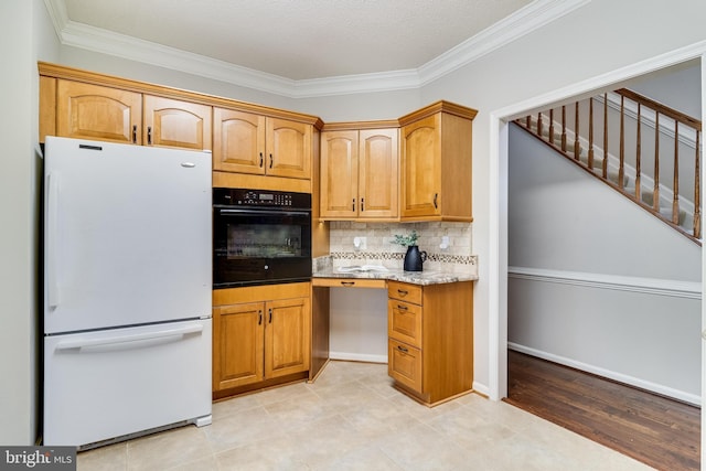 kitchen with decorative backsplash, ornamental molding, freestanding refrigerator, light stone countertops, and black oven