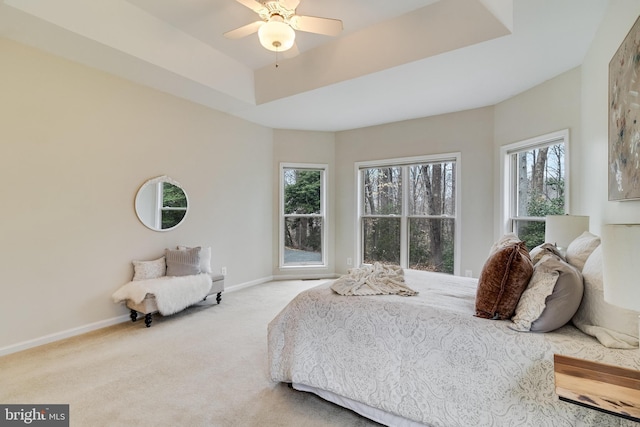 carpeted bedroom featuring ceiling fan, a raised ceiling, and baseboards