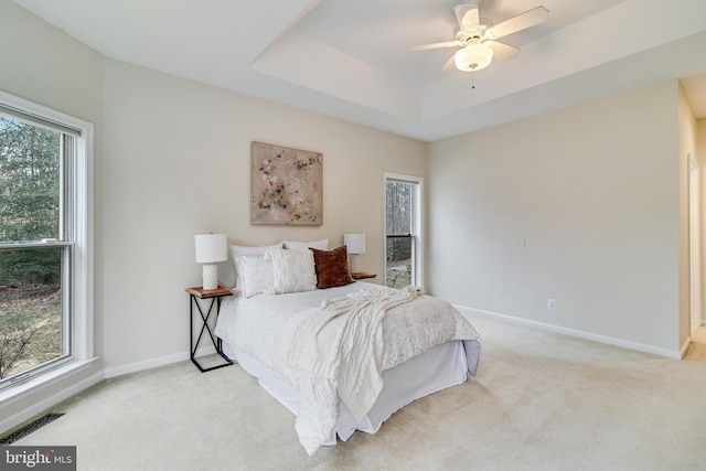 bedroom featuring ceiling fan, light colored carpet, visible vents, baseboards, and a raised ceiling