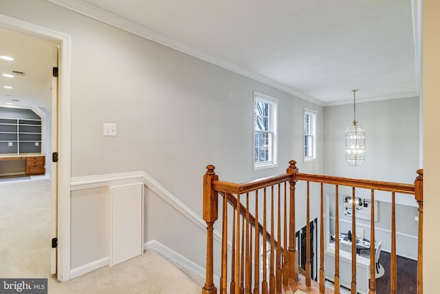 corridor featuring crown molding, light carpet, a notable chandelier, and an upstairs landing