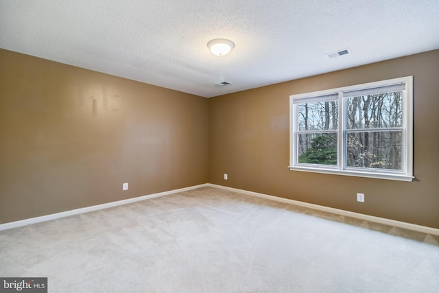 carpeted spare room featuring a textured ceiling, visible vents, and baseboards