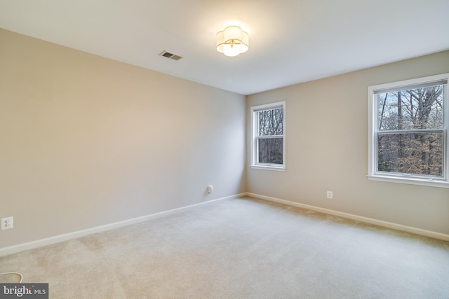 empty room featuring light colored carpet, visible vents, and plenty of natural light