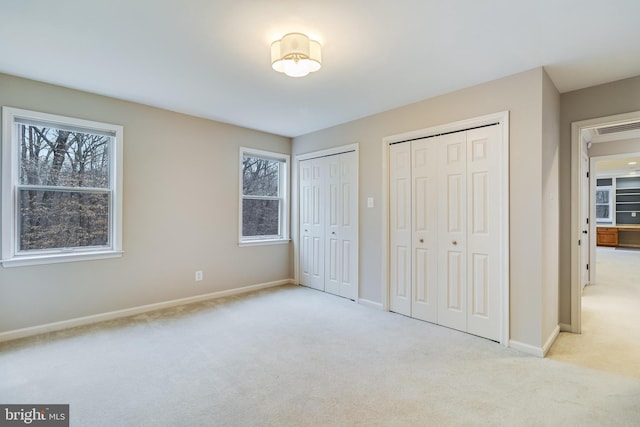 unfurnished bedroom featuring multiple closets, carpet, multiple windows, and baseboards