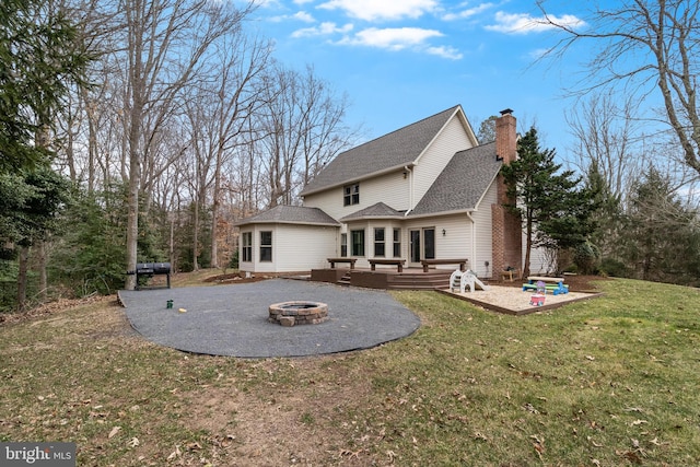 rear view of house featuring an outdoor fire pit, a shingled roof, a chimney, a yard, and a patio area