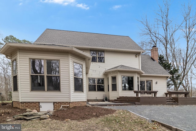 rear view of house with a shingled roof, a chimney, and a deck