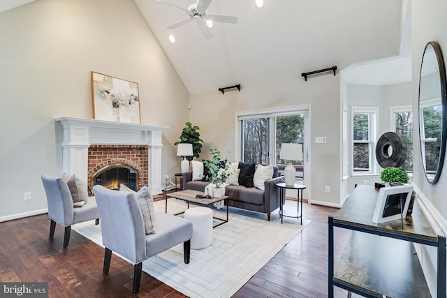 living room with high vaulted ceiling, hardwood / wood-style flooring, a fireplace, a ceiling fan, and baseboards