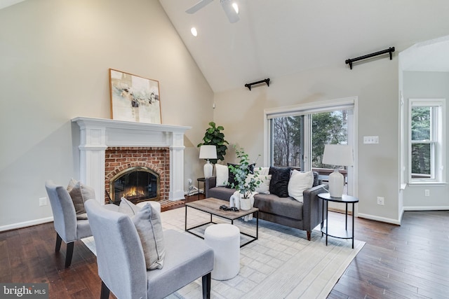 living room with a brick fireplace, baseboards, high vaulted ceiling, and hardwood / wood-style floors