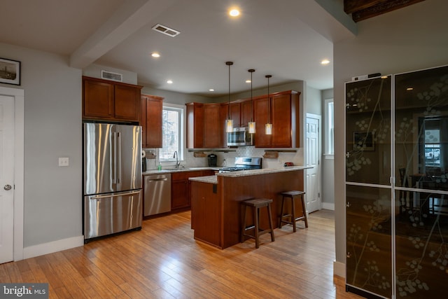 kitchen with beam ceiling, light wood finished floors, visible vents, appliances with stainless steel finishes, and a sink