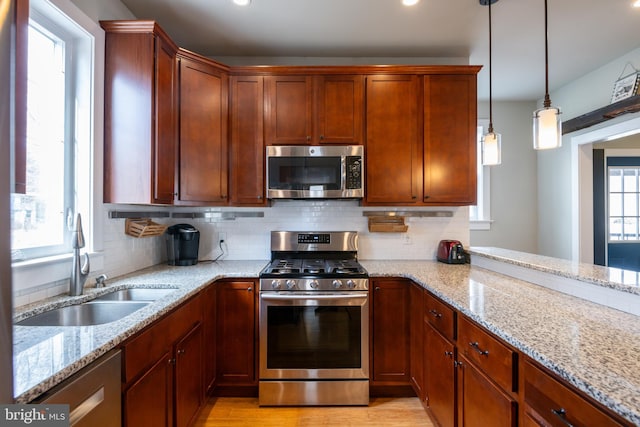 kitchen with light stone countertops, appliances with stainless steel finishes, backsplash, and a sink