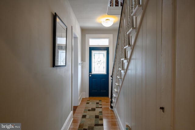 doorway with stairway, wood finished floors, and baseboards