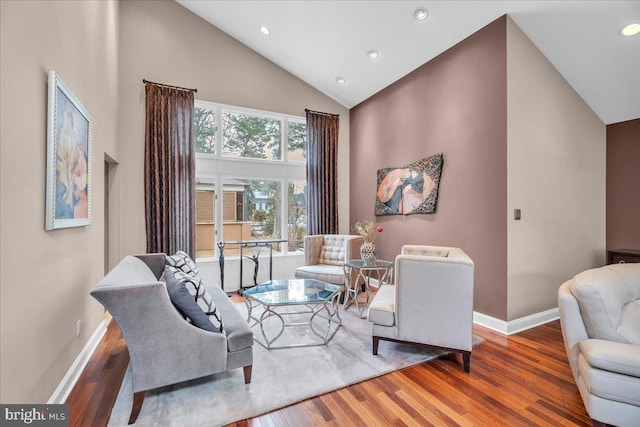 living area with baseboards, high vaulted ceiling, wood finished floors, and recessed lighting