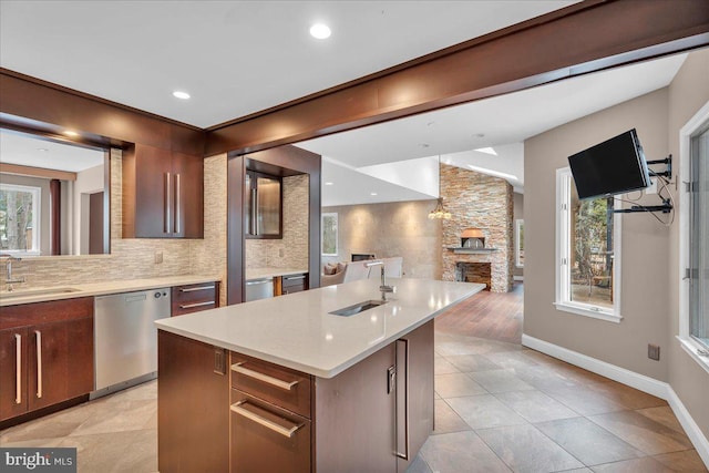 kitchen featuring dishwasher, light countertops, a fireplace, and a sink