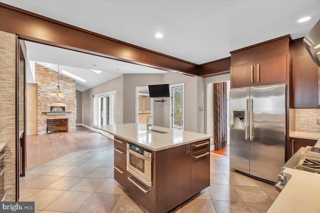 kitchen with light tile patterned floors, a fireplace, light countertops, and stainless steel fridge with ice dispenser