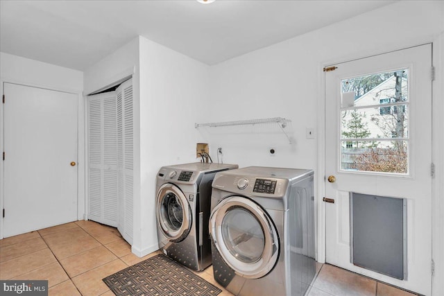 washroom featuring laundry area, washer and clothes dryer, and light tile patterned flooring