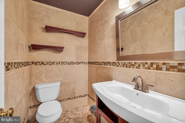 half bathroom with toilet, tile walls, and vanity