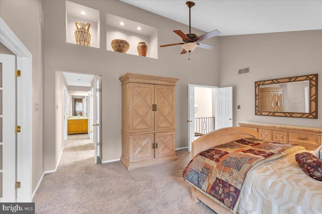 bedroom featuring light colored carpet, visible vents, a high ceiling, and baseboards