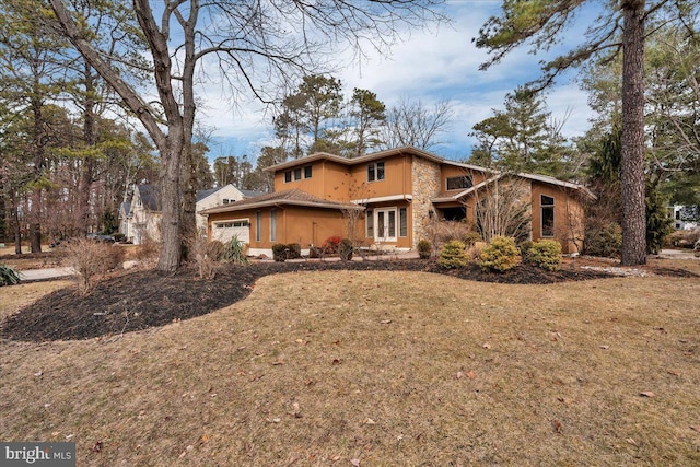 view of front of property with stone siding, stucco siding, an attached garage, and a front yard