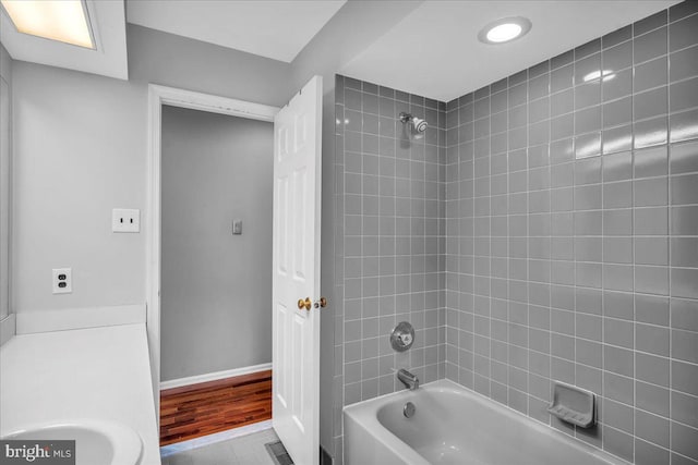 bathroom featuring a sink, wood finished floors, visible vents, baseboards, and shower / washtub combination