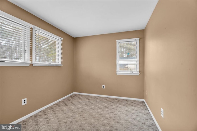 spare room featuring carpet floors and baseboards