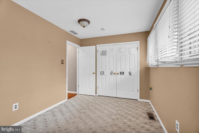 unfurnished bedroom featuring carpet, a closet, visible vents, and baseboards