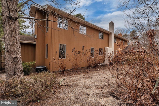 view of home's exterior with a chimney and cooling unit