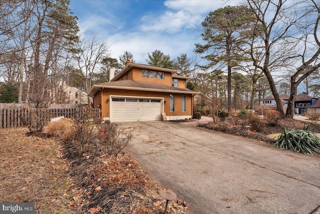 view of front of home with a garage, a chimney, fence, and concrete driveway