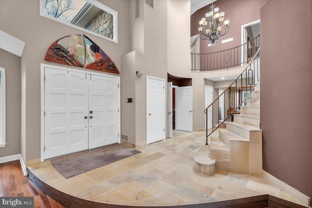 foyer entrance featuring a chandelier, stairs, a towering ceiling, and baseboards