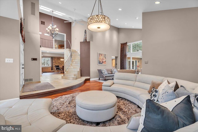 living room featuring an inviting chandelier, visible vents, stairway, and wood finished floors