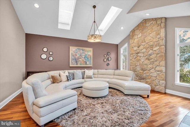 living room featuring a skylight, a healthy amount of sunlight, baseboards, and wood finished floors