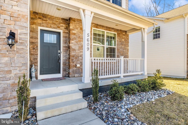 doorway to property with stone siding and covered porch