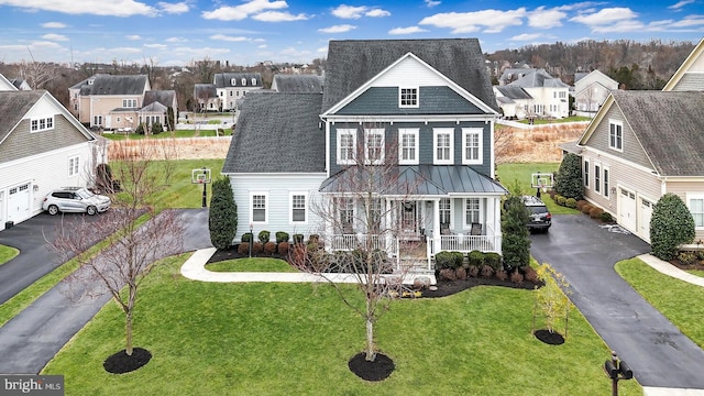 view of front of property featuring a standing seam roof, a porch, a residential view, and aphalt driveway