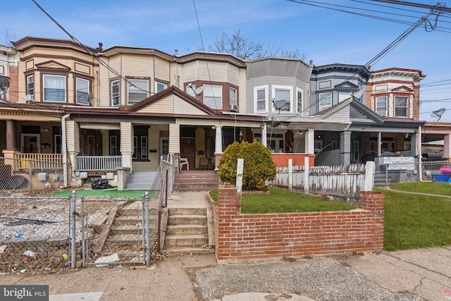 townhome / multi-family property featuring a fenced front yard, a gate, and a porch