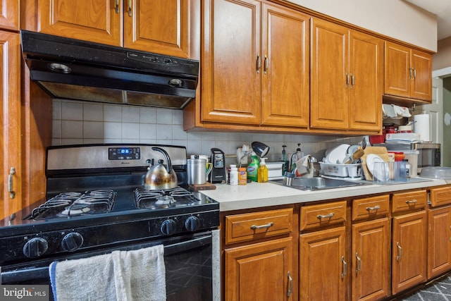 kitchen featuring a sink, brown cabinetry, range with gas cooktop, and under cabinet range hood